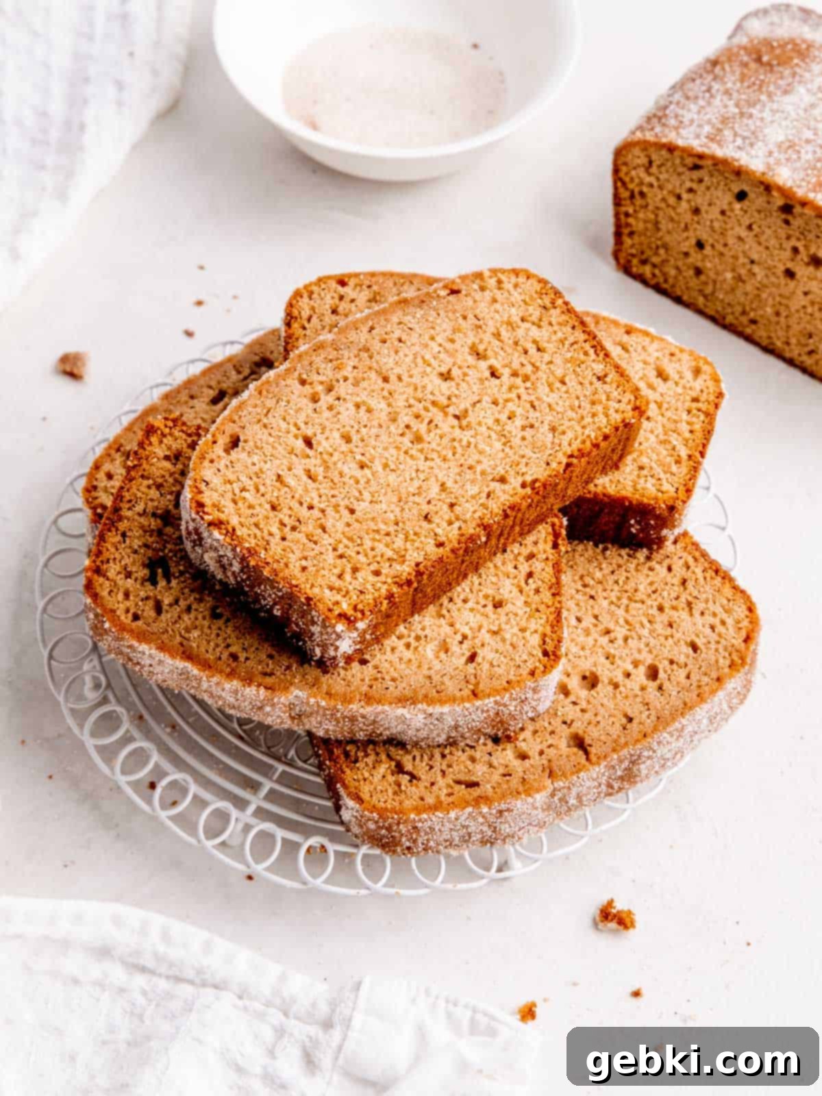 Spiced Apple Cider Loaf Cake 2 Stacked slices of moist Apple Cider Donut Loaf Cake on a cooling rack, showing its beautiful texture and chai sugar topping.