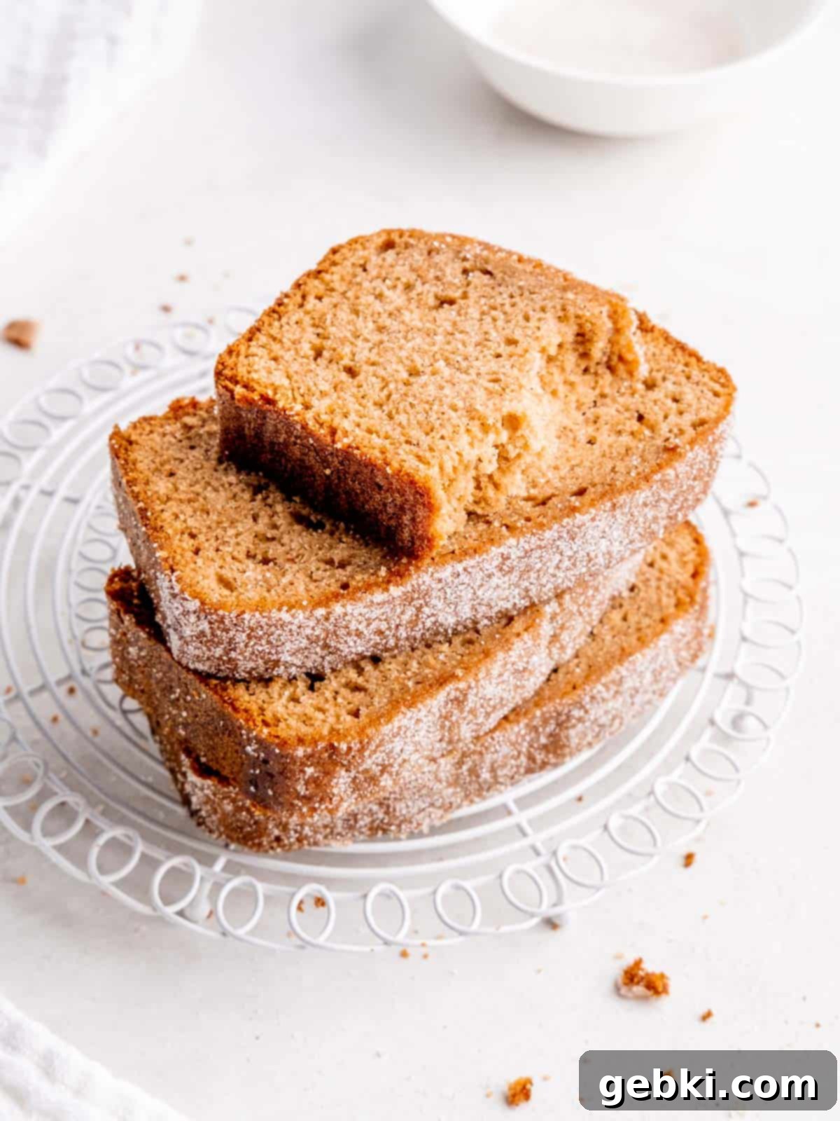 Spiced Apple Cider Loaf Cake 9 A beautiful stack of perfectly cut Apple Cider Donut Loaf Cake slices, showcasing the moist interior and spiced sugar topping on a white cooling rack.