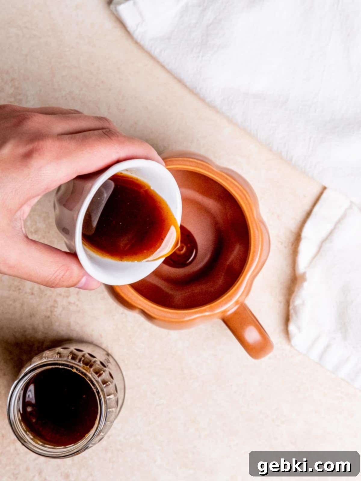 Pouring rich pumpkin spice syrup into a coffee mug, preparing for a homemade latte.