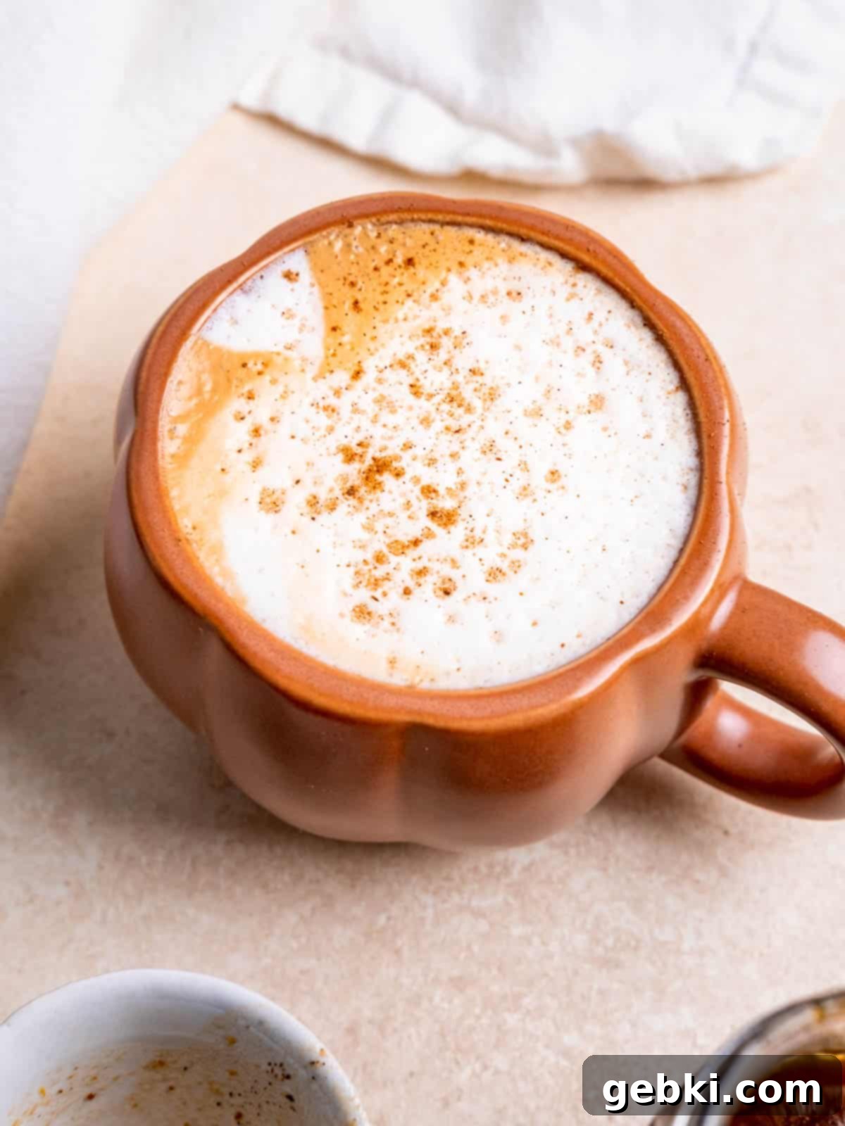 A cozy homemade pumpkin spice latte in a charming coffee mug, topped with whipped cream and a sprinkle of spice.