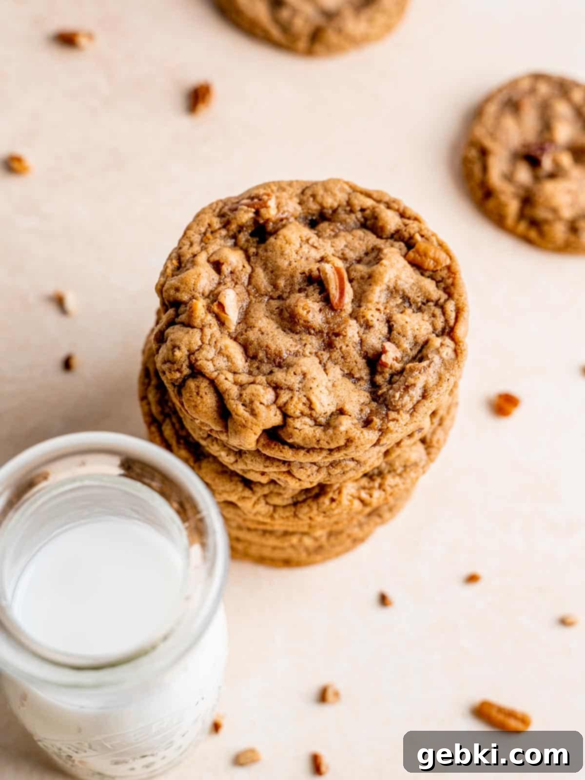 A stack of maple pecan cookies next to a glass of milk.