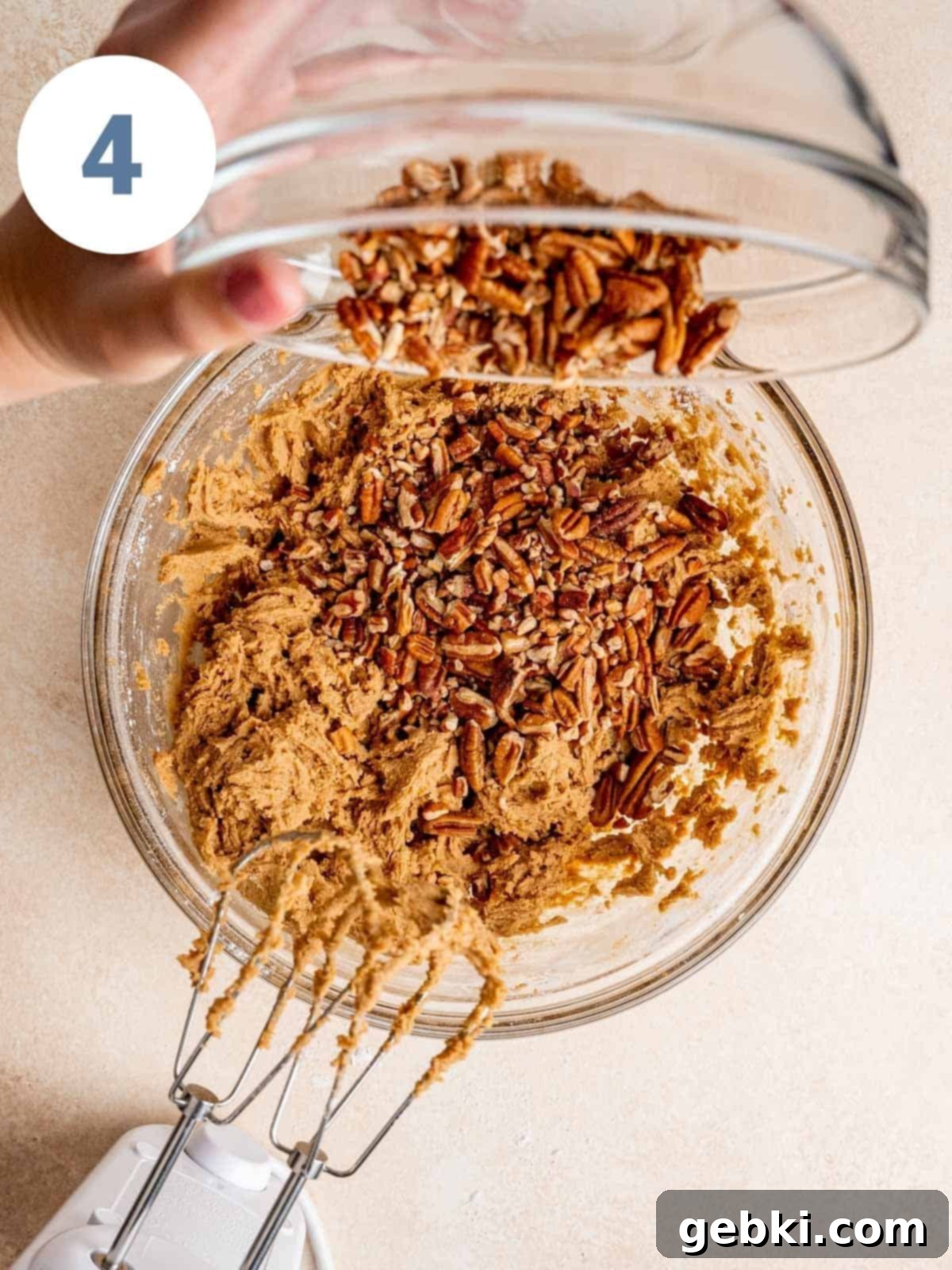 Pouring chopped pecans into maple cookie dough.