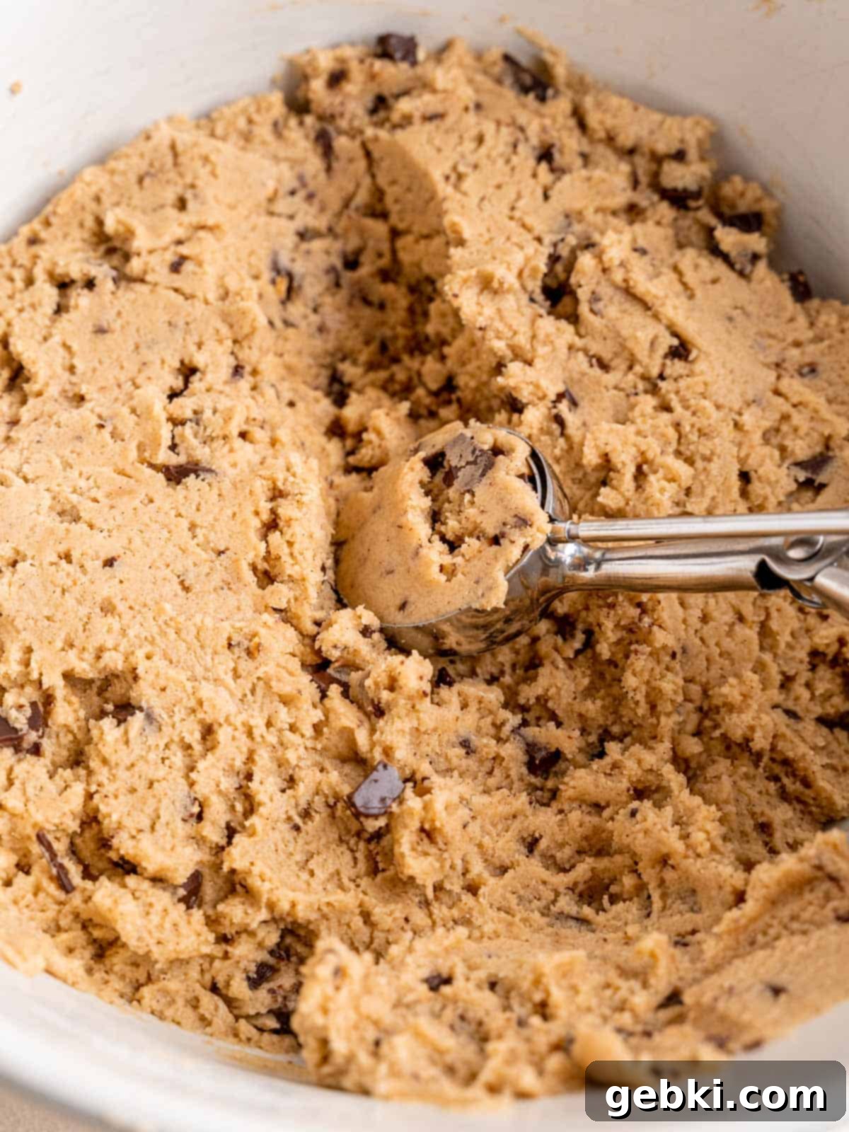 Nutty Browned Butter Snickerdoodle Cookies 7 Cookie dough with cinnamon, cardamom, browned butter and chocolate toffee bits in a bowl with a cookie scoop.