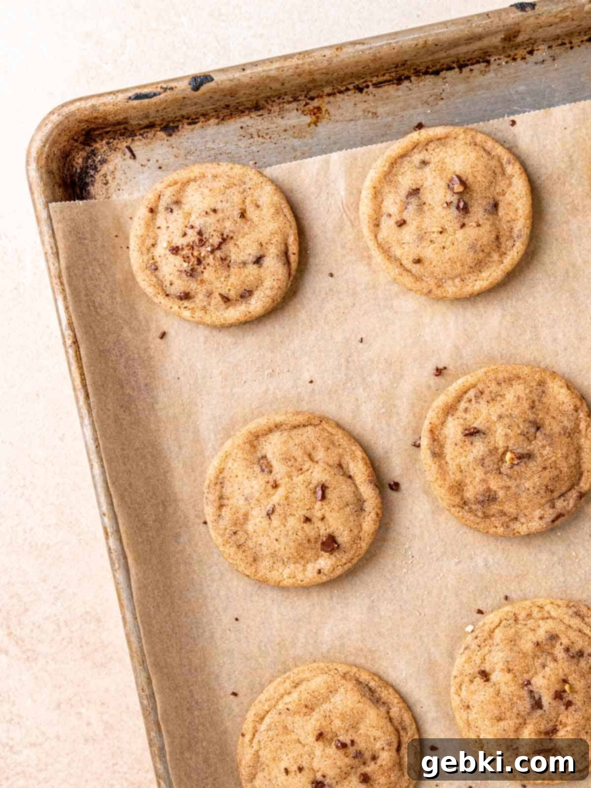 Nutty Browned Butter Snickerdoodle Cookies 9 Baked snickerdoodle cookies on a parchment-lined sheet.