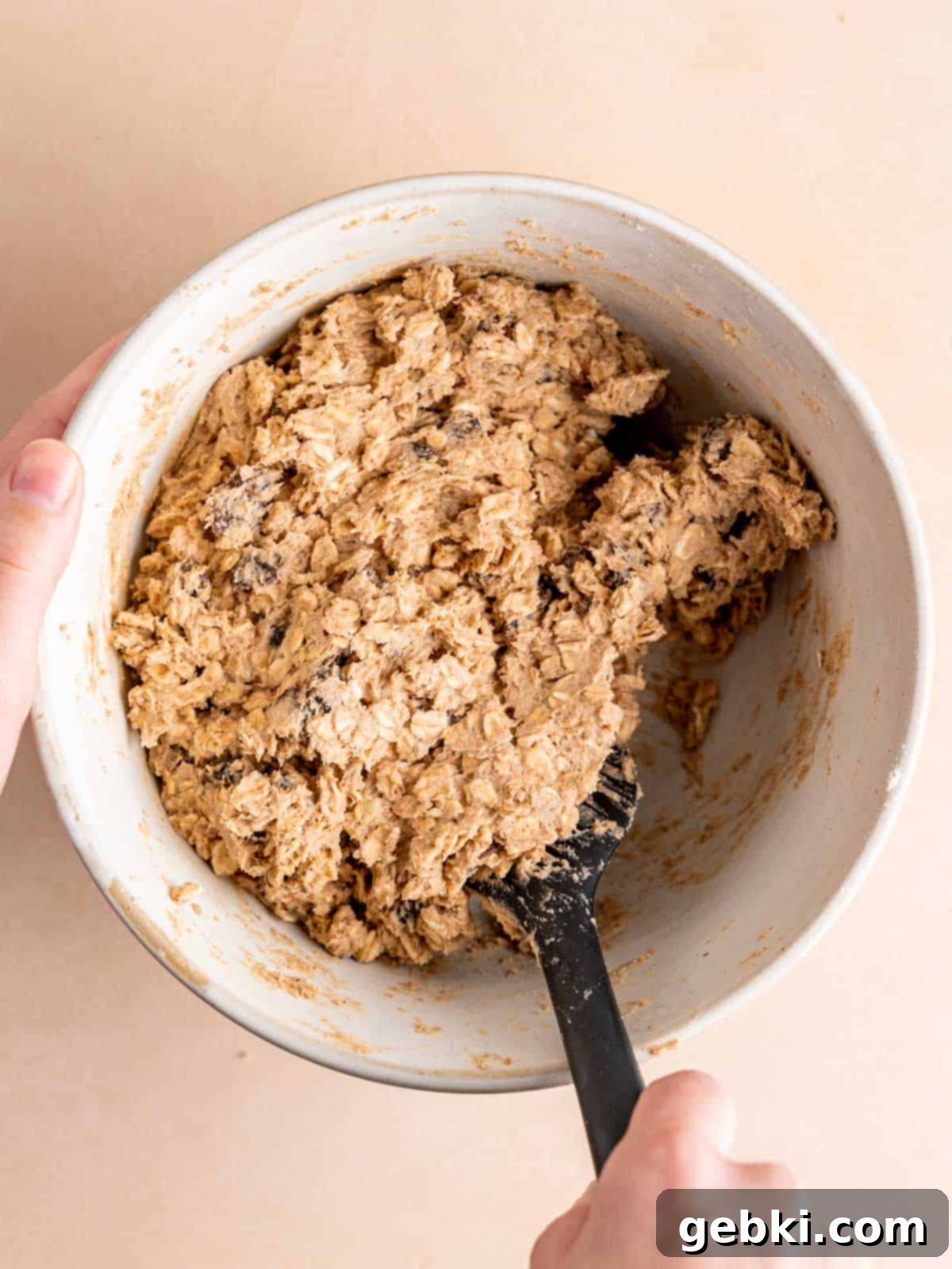 Classic Chewy Oatmeal Raisin Cookies 6 Oatmeal raisin cookie dough in a mixing bowl with a spatula, showing the oats and raisins.