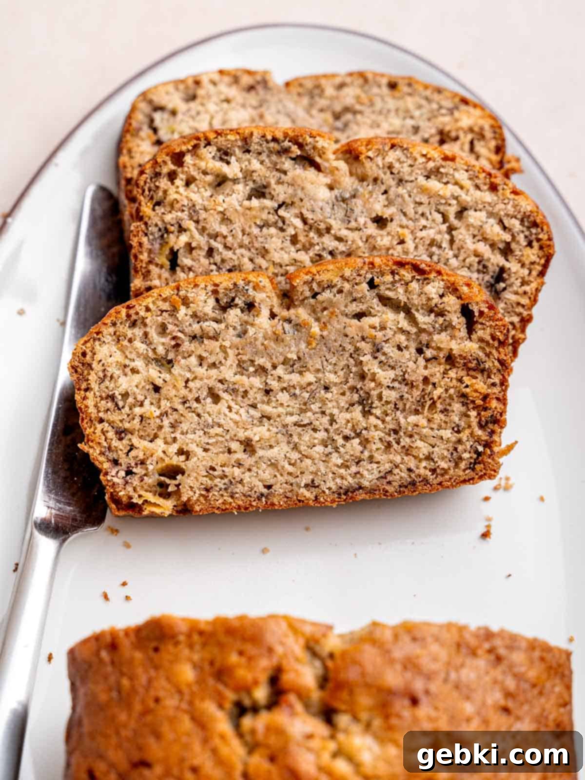 Effortless One-Bowl Banana Bread 2 Slices of homemade moist banana bread on a plate with a knife.