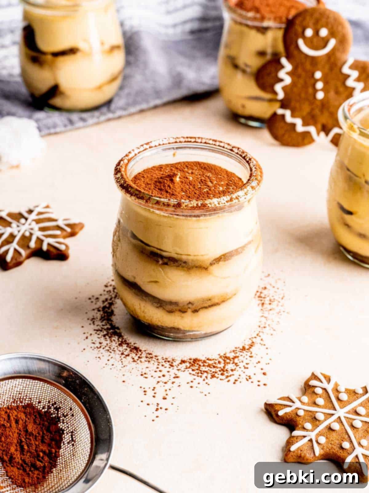 A jar of gingerbread tiramisu with cocoa sprinkled on top, ready to be enjoyed as a festive dessert.