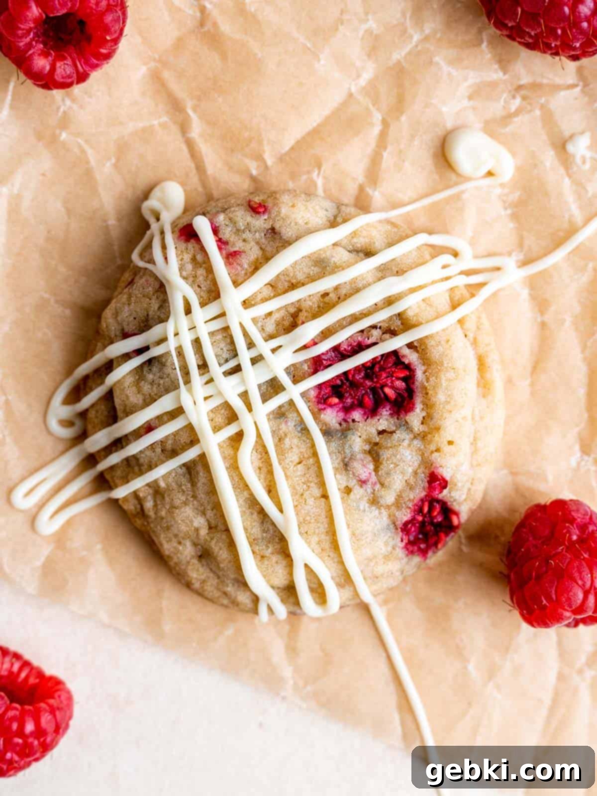 Top view of a cheesecake stuffed raspberry cookie drizzled with white chocolate.