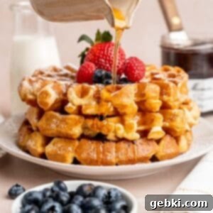 Fluffy Golden Homemade Belgian Waffles 10 Pouring maple syrup on top of a stack of fluffy, golden-brown Belgian waffles.
