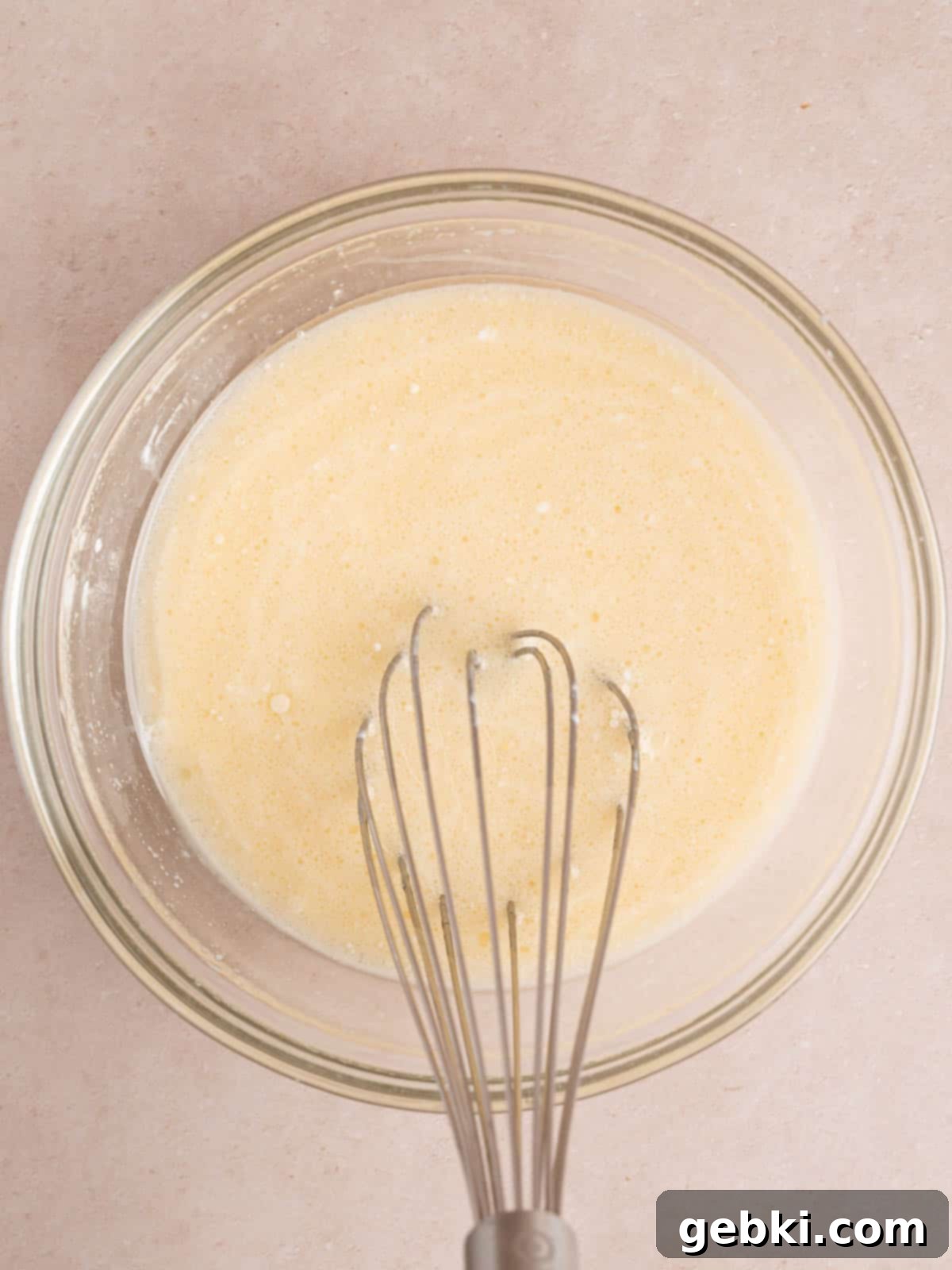 Fluffy Golden Homemade Belgian Waffles 5 Whisking a large egg, whole milk, sour cream, vegetable oil, and vanilla extract in a separate bowl to combine wet ingredients.