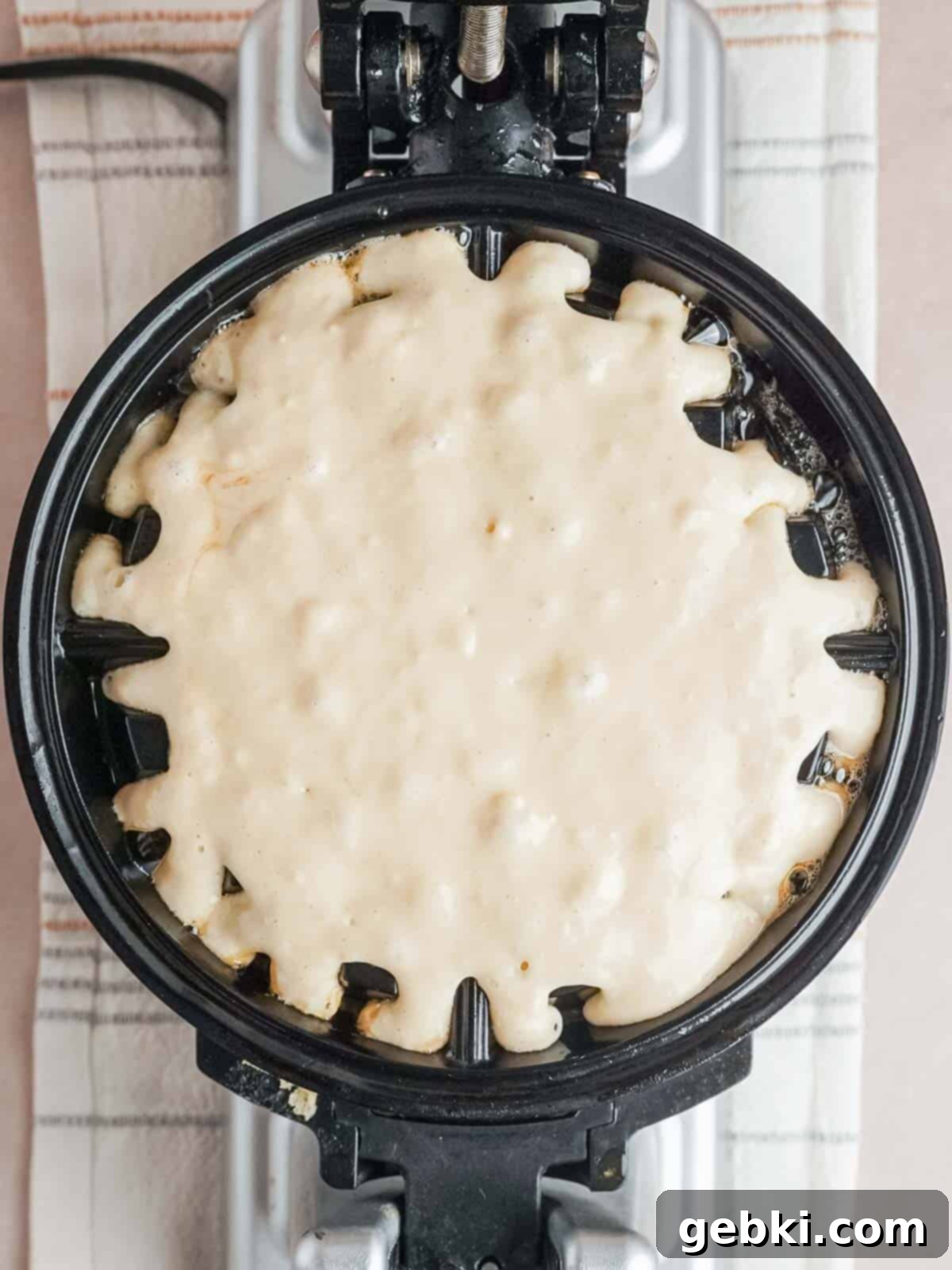 Fluffy Golden Homemade Belgian Waffles 7 Pouring prepared waffle batter into a preheated, greased waffle maker for cooking.