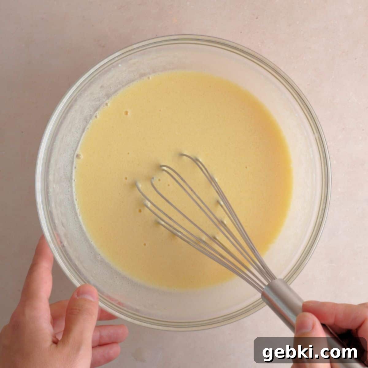 Decadent Double Chocolate Loaf 5 A medium mixing bowl containing beaten eggs, plain kefir, vegetable oil, and vanilla extract, being whisked until the mixture is smooth and well emulsified.