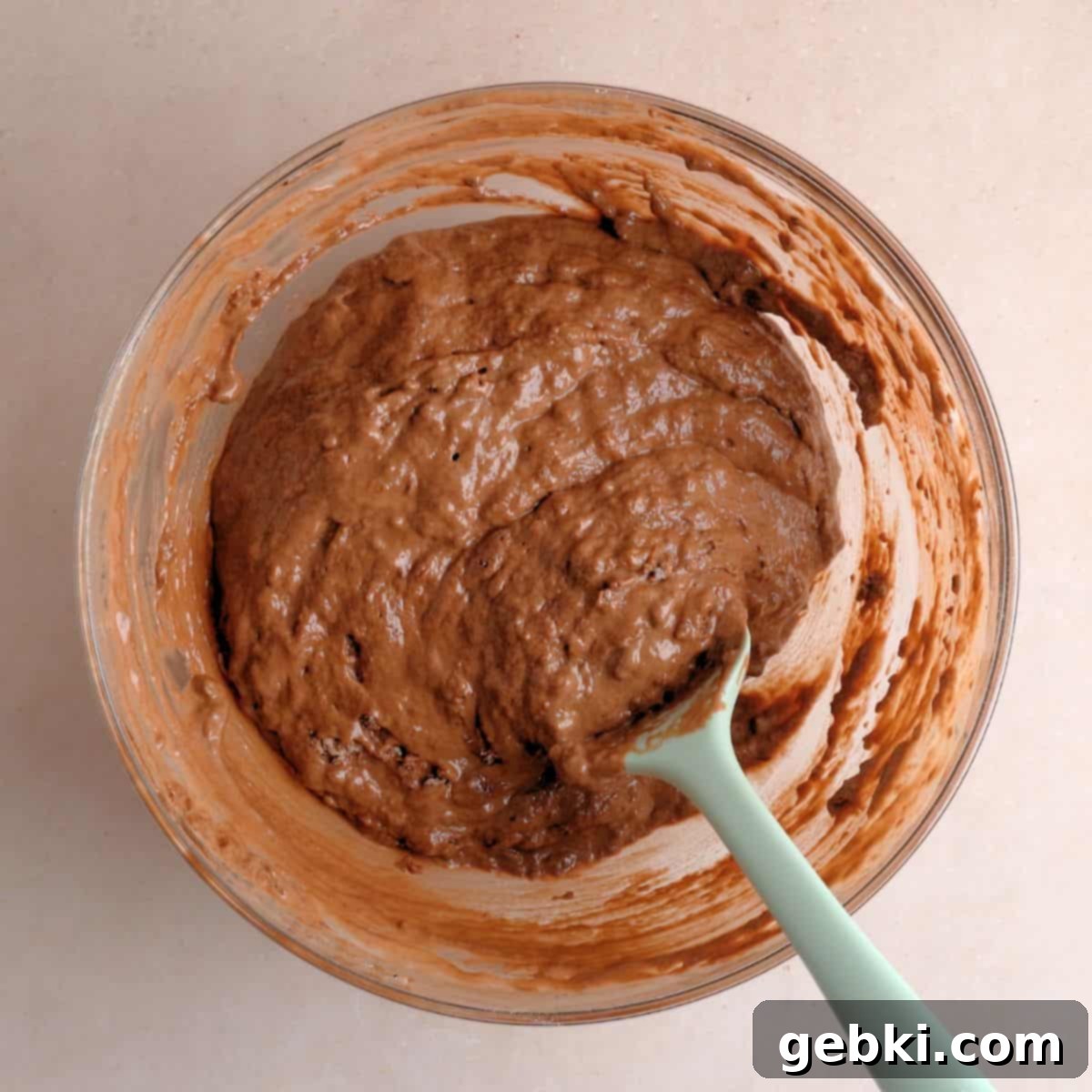 Decadent Double Chocolate Loaf 6 Chocolate cake batter in a large mixing bowl, partially mixed with a rubber spatula, showing a few dry streaks before the final incorporation of hot water.