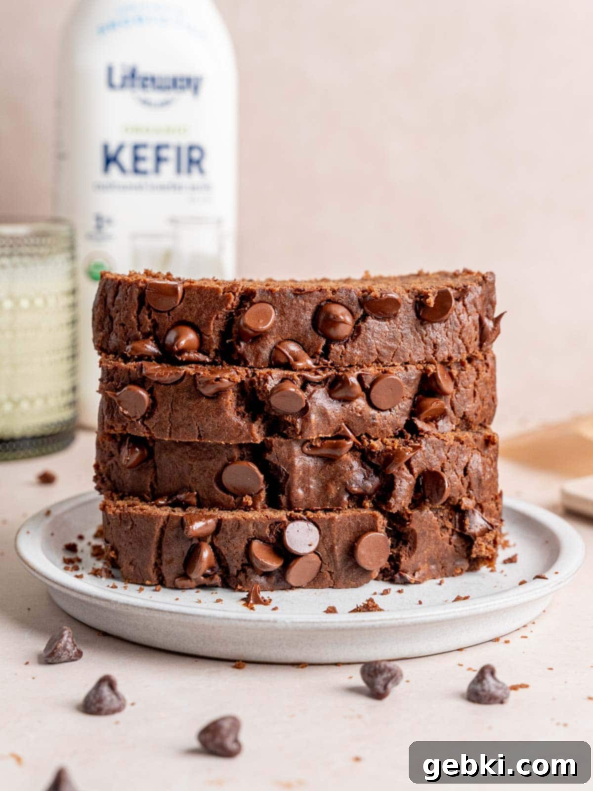 Decadent Double Chocolate Loaf 10 A stack of perfectly sliced, moist double chocolate loaf cake slices presented elegantly on a white plate, highlighting their rich color and tender texture.