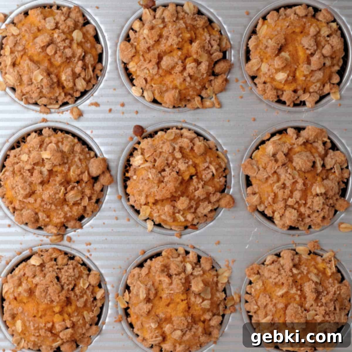 Effortless Pumpkin Oatmeal Muffins with Perfect Crumbly Streusel 11 Freshly baked pumpkin oatmeal muffins with a golden brown streusel topping cooling in a muffin tin, having just come out of the oven.