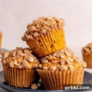 Effortless Pumpkin Oatmeal Muffins with Perfect Crumbly Streusel 14 A stack of golden pumpkin oatmeal muffins with a streusel topping, sitting on a white plate, ready to be enjoyed.
