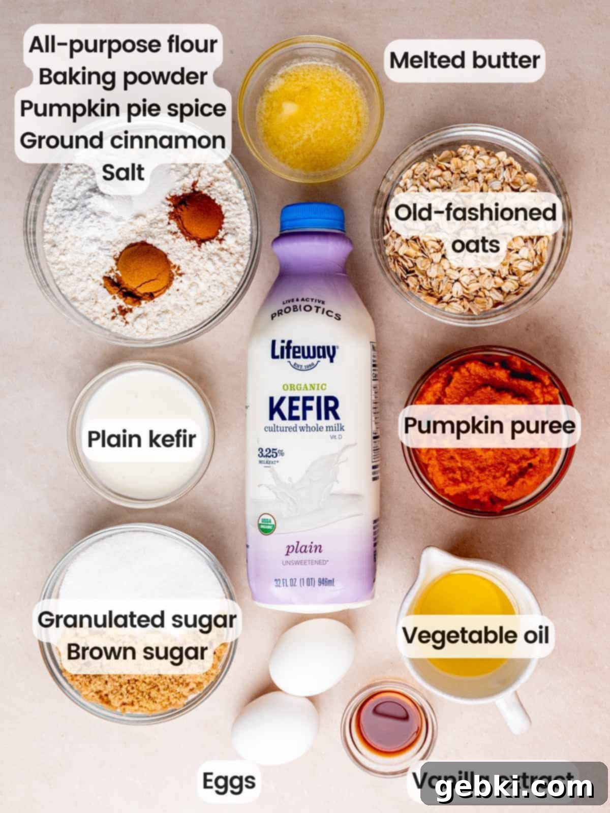 Effortless Pumpkin Oatmeal Muffins with Perfect Crumbly Streusel 3 A flat lay photograph displaying all the ingredients needed to make pumpkin oatmeal muffins, including flour, oats, pumpkin puree, eggs, kefir, and various spices, laid out on a surface.