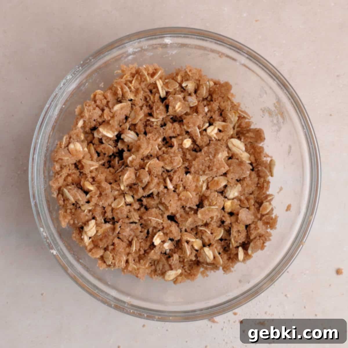 Effortless Pumpkin Oatmeal Muffins with Perfect Crumbly Streusel 4 Close-up of a bowl containing a mixture of flour, oats, brown sugar, and cinnamon, with melted butter being stirred in to create a crumbly, wet sand-like streusel texture.