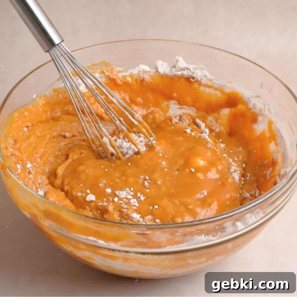 Effortless Pumpkin Oatmeal Muffins with Perfect Crumbly Streusel 7 Pumpkin muffin batter in a bowl after dry ingredients have been stirred in, showing a few remaining streaks of flour, indicating it's perfectly mixed without overworking.