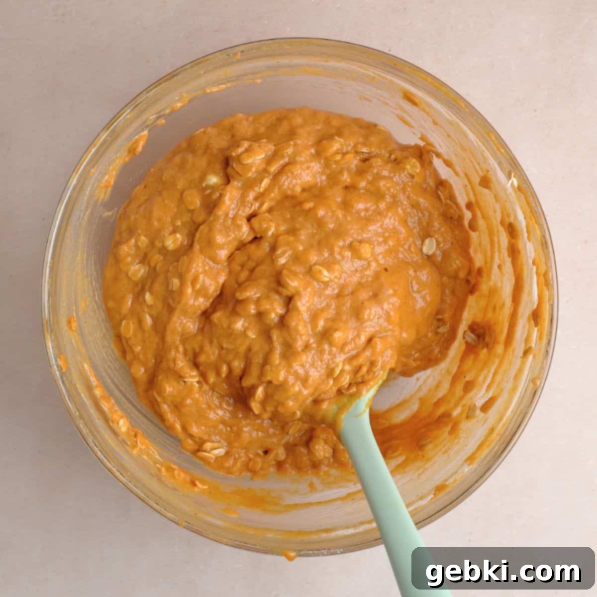 Effortless Pumpkin Oatmeal Muffins with Perfect Crumbly Streusel 8 Old-fashioned oats being gently folded into the pumpkin muffin batter in a bowl, ensuring even distribution throughout the mixture.