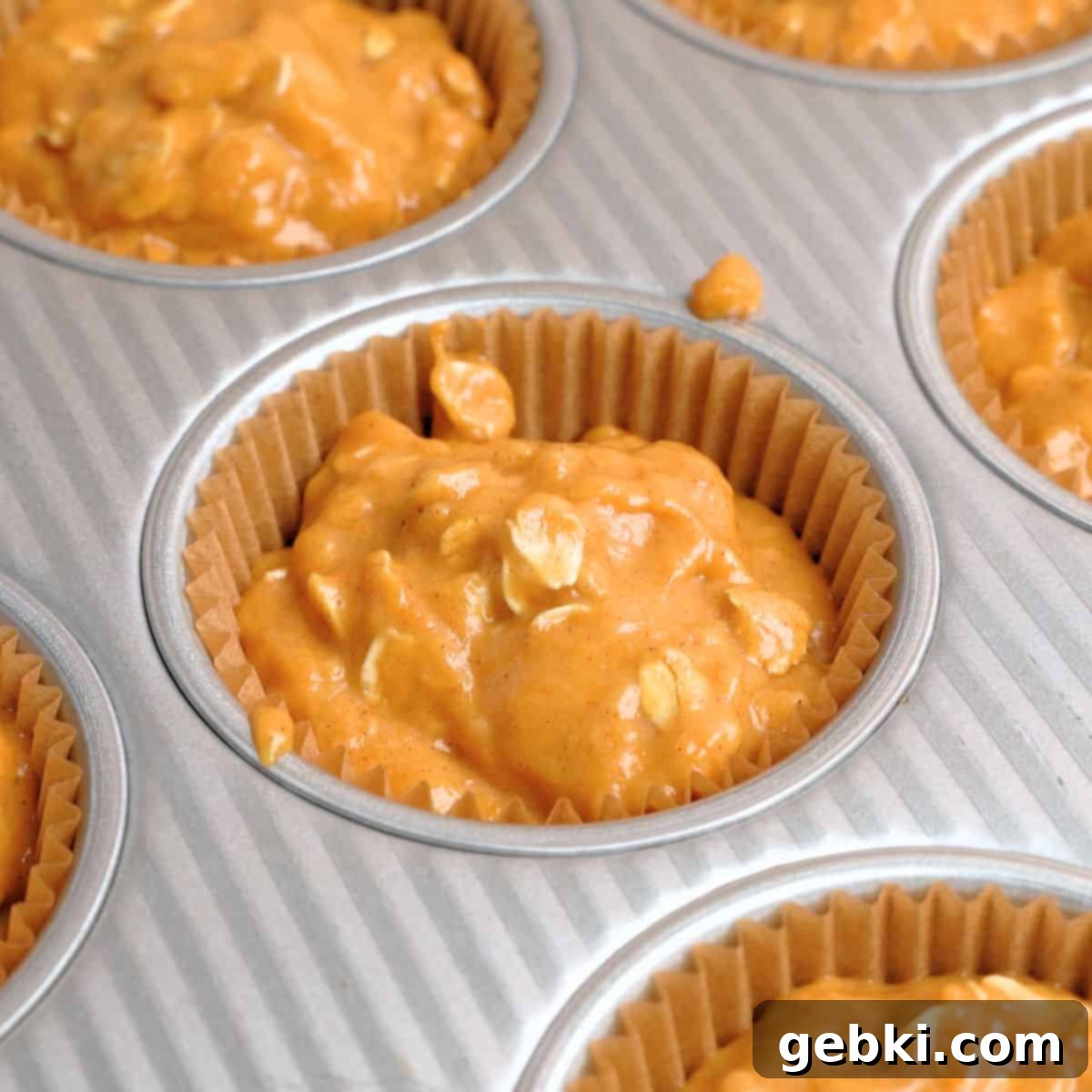 Effortless Pumpkin Oatmeal Muffins with Perfect Crumbly Streusel 9 A muffin pan with cups lined and filled about three-quarters full with pumpkin oatmeal muffin batter, ready for the streusel topping.