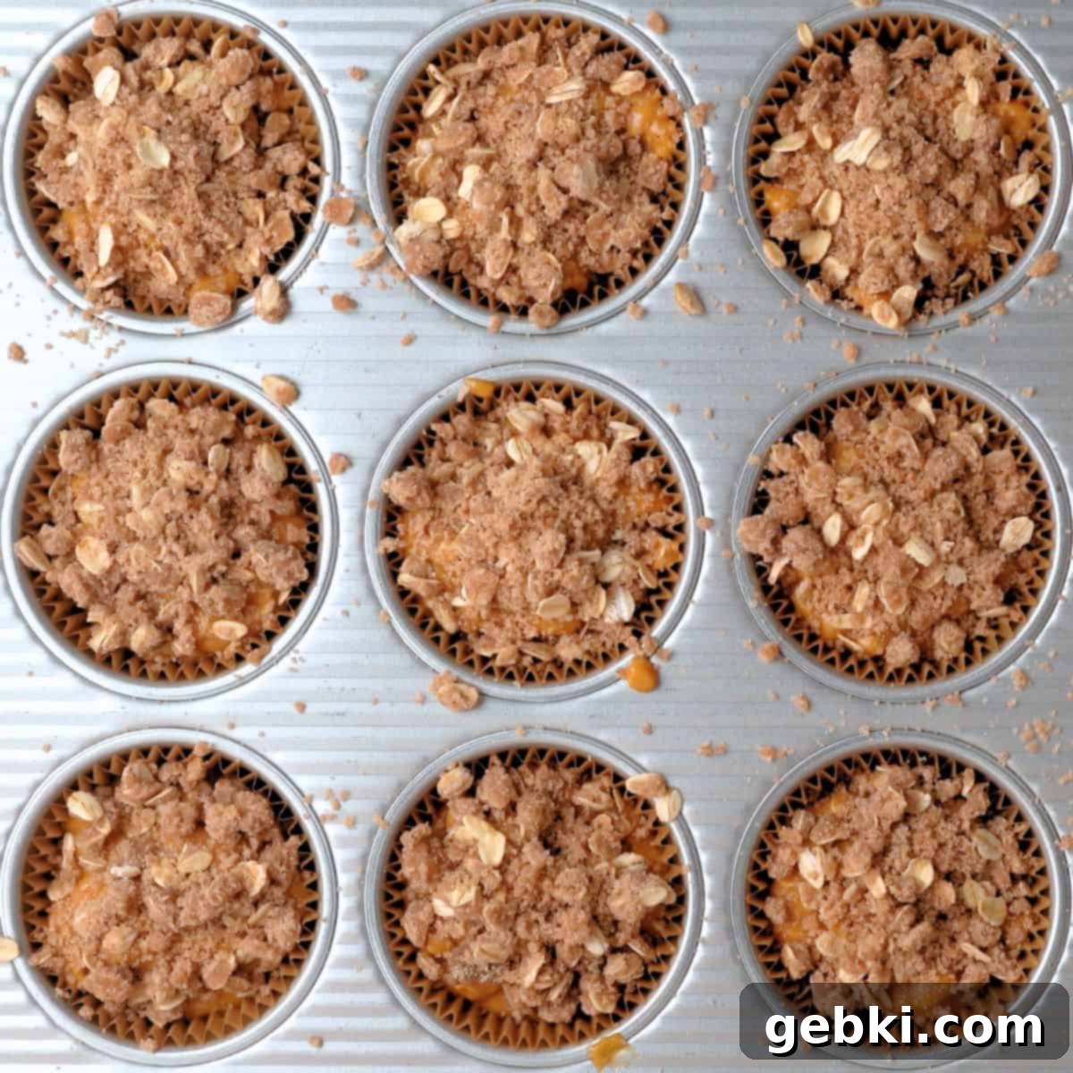 Effortless Pumpkin Oatmeal Muffins with Perfect Crumbly Streusel 10 A muffin tin with unbaked pumpkin oatmeal muffin batter, generously topped with cinnamon oat streusel, ready to be baked.
