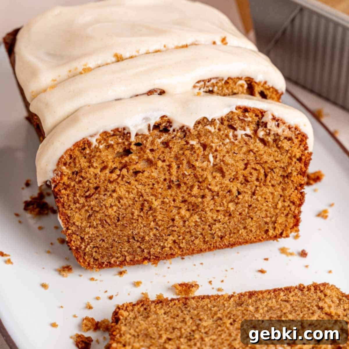 Simple Spiced Cake with Decadent Brown Butter Cream Cheese Frosting 2 A spice cake loaf cut into slices with cream cheese frosting spread on top.