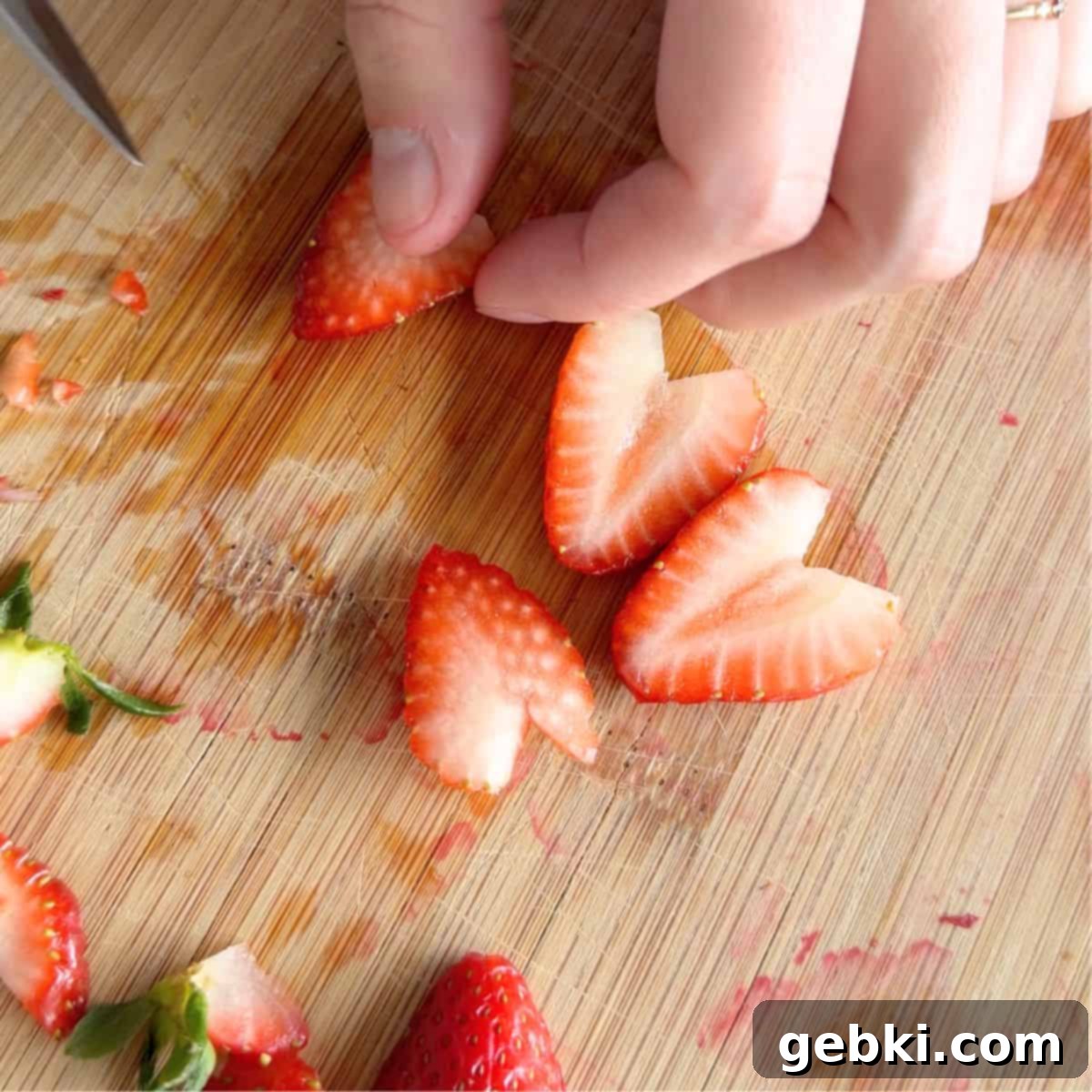 Strawberry Nutella Dream Crepes 5 A person's hands slicing strawberries into thin slices on a cutting board.