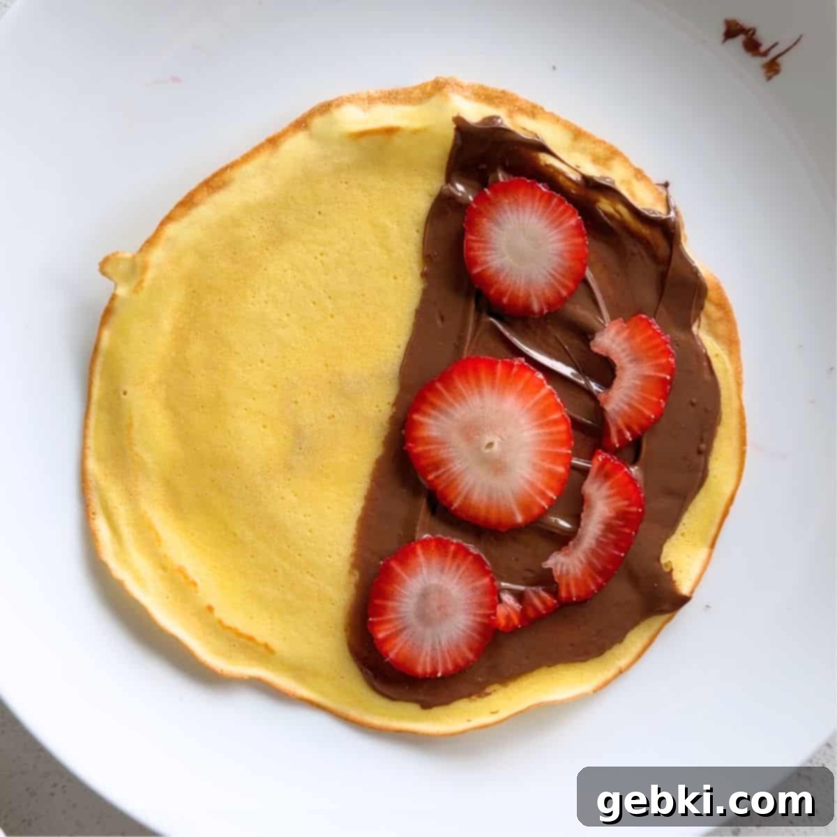 Strawberry Nutella Dream Crepes 8 Spreading Nutella on half of a crepe and topping it with fresh strawberry slices.
