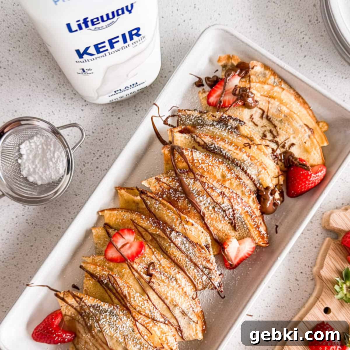 Strawberry Nutella Dream Crepes 10 A stack of Nutella and strawberry crepes on a plate, accompanied by a bottle of Lifeway kefir.