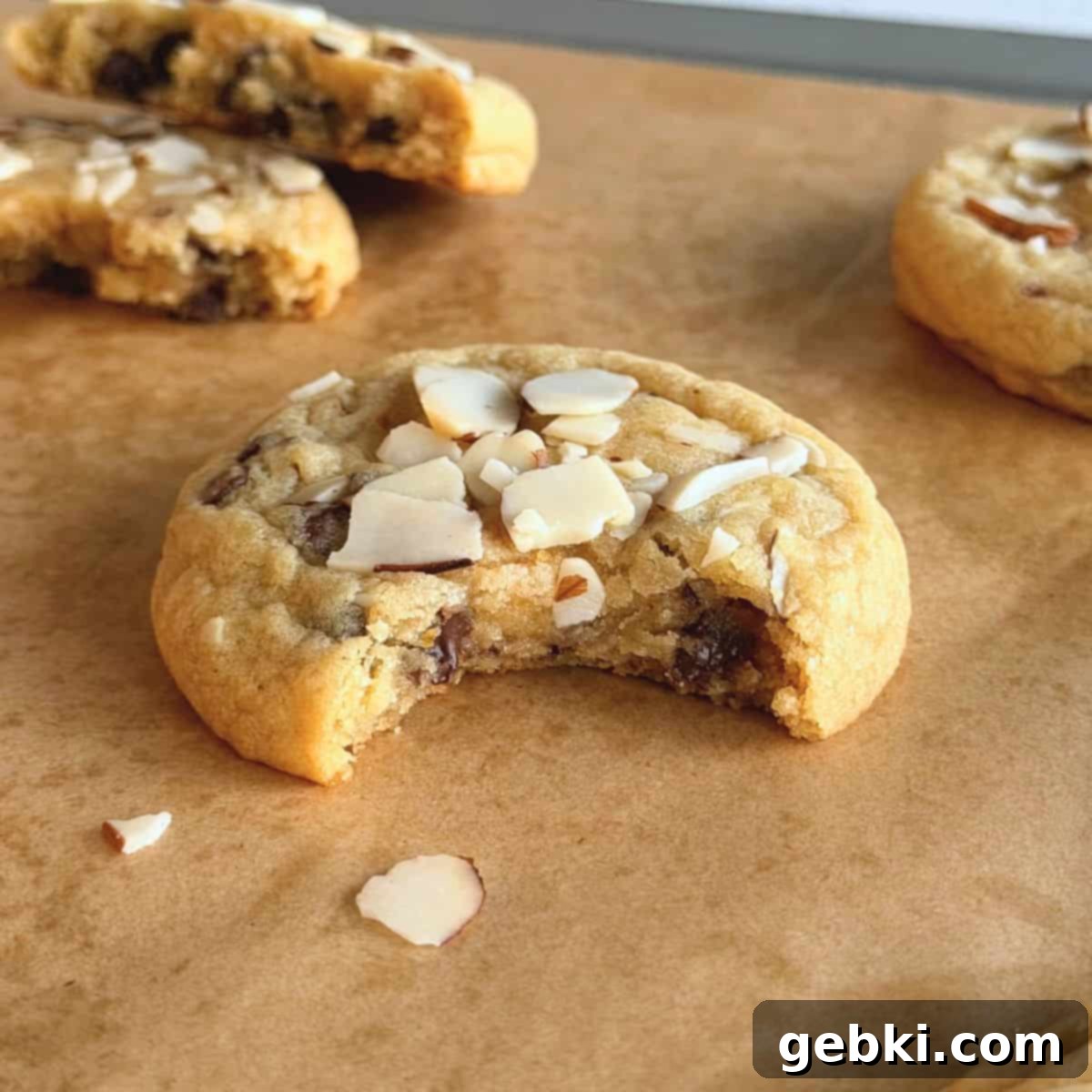 Orange Almond Chocolate Chunk Cookies 2 A close-up of an orange almond chocolate chip cookie with a bite taken out of it, showcasing its texture and ingredients.