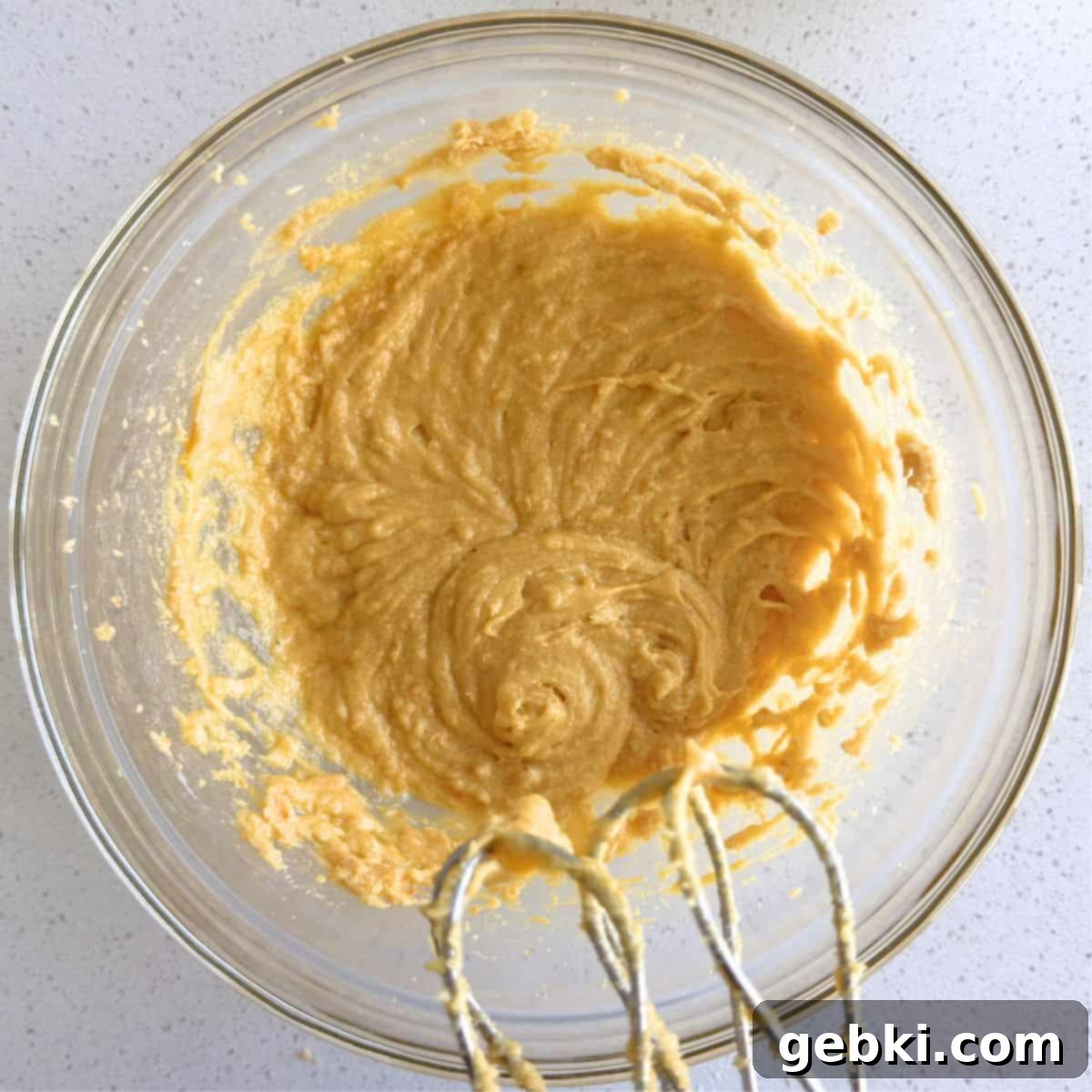 Softened butter, brown sugar, orange sugar, egg, vanilla extract, and almond extract all mixed together in a bowl, forming the base of the cookie dough.