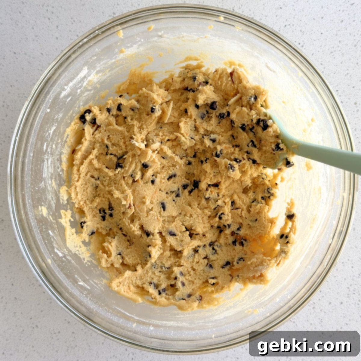 Mini chocolate chips and sliced almonds being folded into the cookie dough, adding texture and flavor.