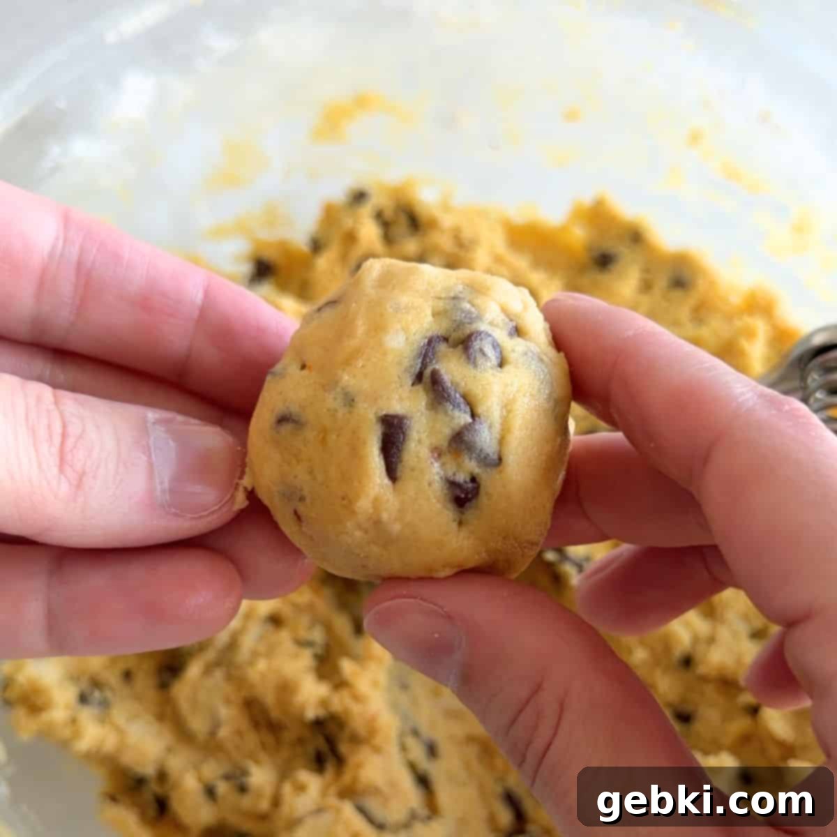 Orange almond chocolate chip cookie dough being rolled into balls, ready for baking.